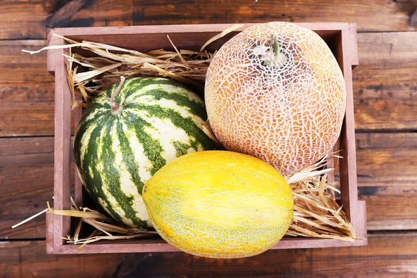 Melones y sandías en caja de madera sobre fondo de madera —  Fotos de Stock