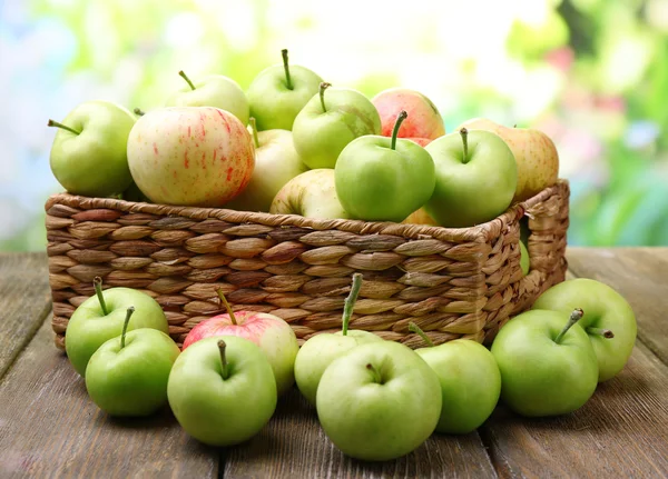 Manzanas maduras en canasta sobre mesa sobre fondo natural —  Fotos de Stock