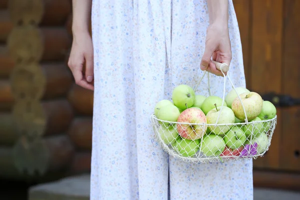 Girl holding basket of apples outdoors — Stock Photo, Image
