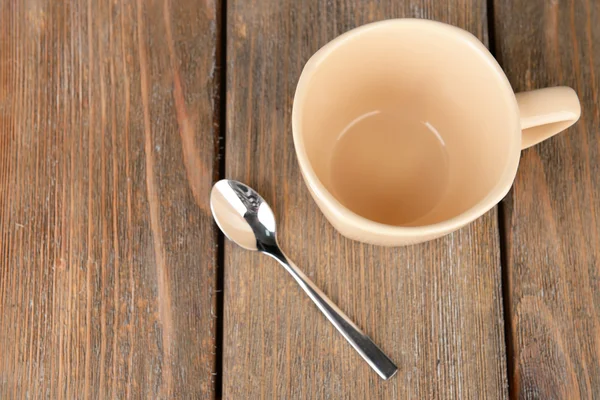 Empty cup with tea spoon on wooden background — Stock Photo, Image