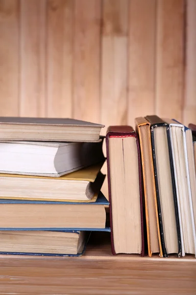 Livros sobre mesa de madeira no fundo da parede de madeira — Fotografia de Stock