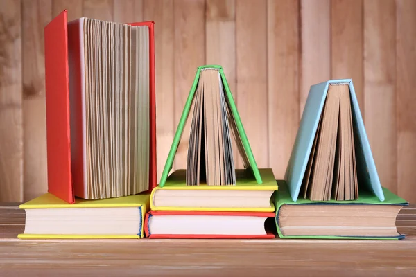 Libros sobre mesa de madera sobre fondo de pared de madera — Foto de Stock