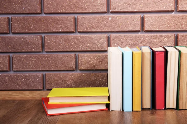 Bücher auf Holztisch auf Backsteinwand Hintergrund — Stockfoto