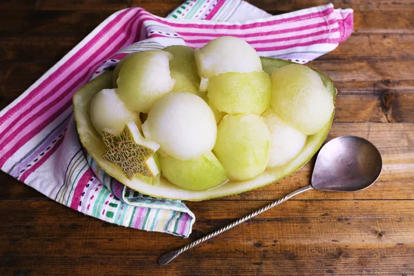 Melon in melon peel on napkin on wooden background — Stock Photo, Image