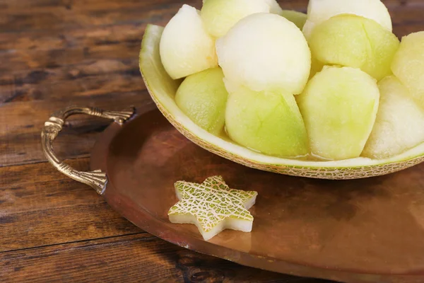 Melon in melon peel on metal tray on wooden background — Stock Photo, Image