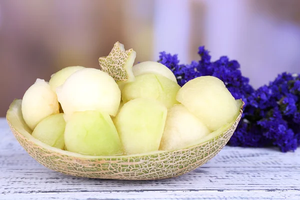 Melón en piel de melón y flores sobre mesa de madera sobre fondo natural — Foto de Stock