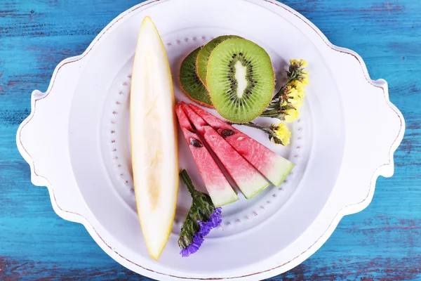 Rodajas de melón, kiwi y sandía en plato sobre fondo de madera — Foto de Stock