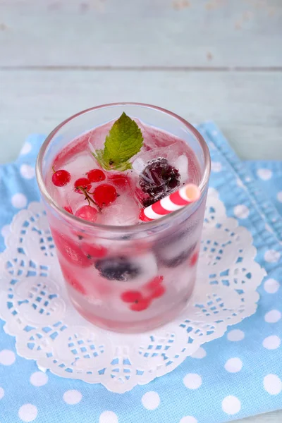 Холодные коктейли с лесными ягодами, замороженные в кубиках льда на фоне цвета дерева — стоковое фото