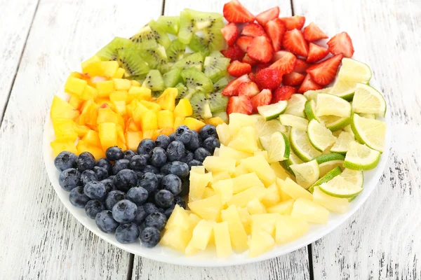 Frutas en rodajas en plato sobre mesa de madera — Foto de Stock