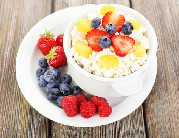 Cottage cheese with fruits and berries in bowl on wooden table — Stock Photo, Image