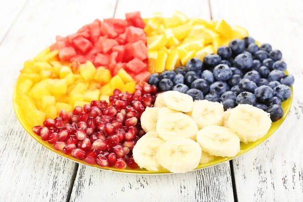 Frutas en rodajas en plato sobre mesa de madera —  Fotos de Stock