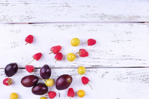 Belles prunes mûres et baies sur table en bois close-up — Photo