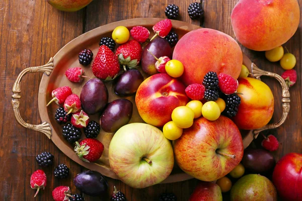 Different berries and fruits on tray on wooden table close-up — Stock Photo, Image