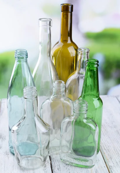 Пустые стеклянные бутылки на столе на ярком фоне — стоковое фото