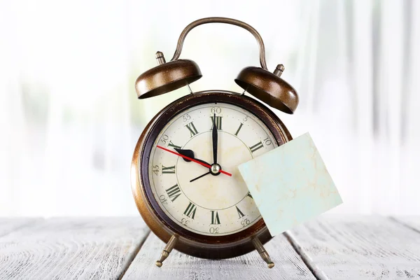 Alarm clock with sticker on bright background — Stock Photo, Image