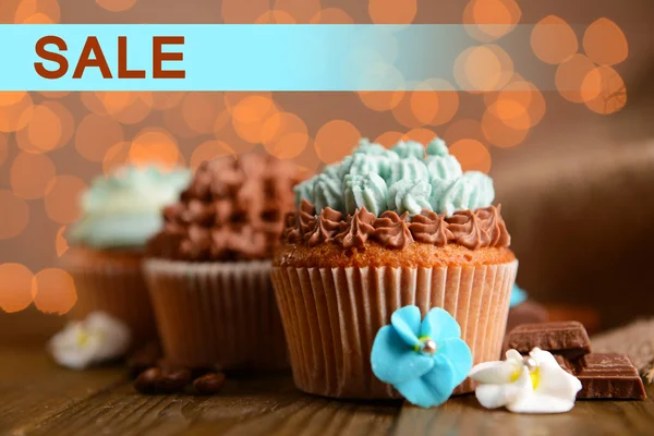 Concept of discount. Tasty cupcakes with butter cream on lights background — Stock Photo, Image