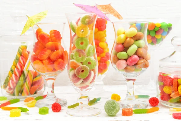 Different colorful fruit candy in glasses on table on light background — Stock Photo, Image