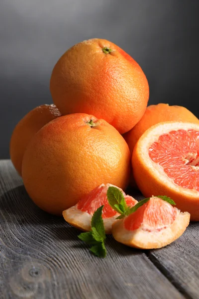 Ripe grapefruits on wooden board, on dark color background — Stock Photo, Image