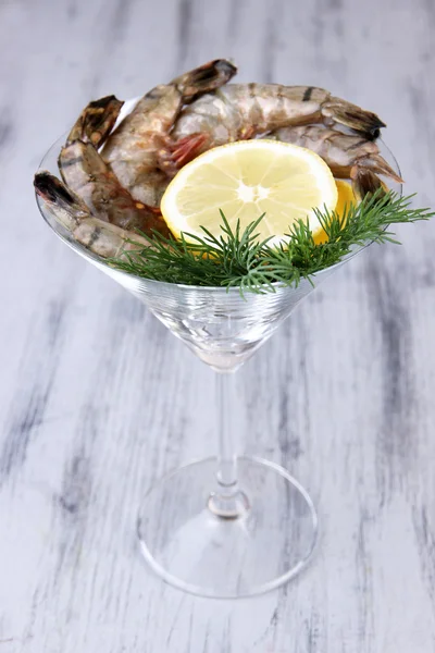 Martini copa de gambas frescas sabrosas con limón y eneldo sobre fondo de madera gris — Foto de Stock