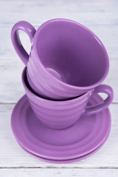 Tasse violette et soucoupes sur fond de table en bois — Photo