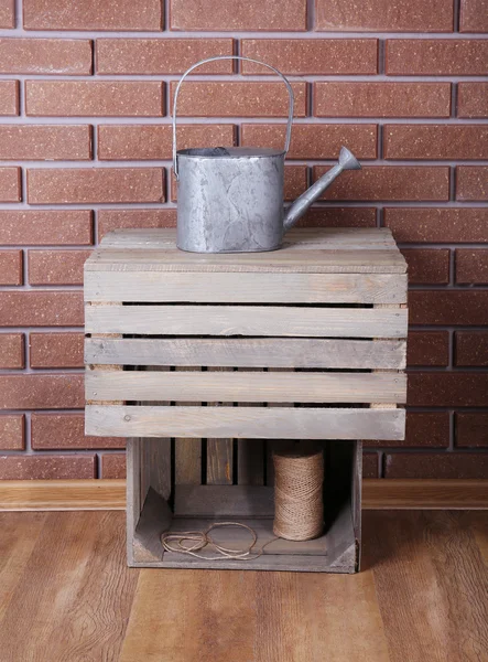 Rectangular wooden boxes on the floor in front of brick wall with watering can and rope — Stock Photo, Image