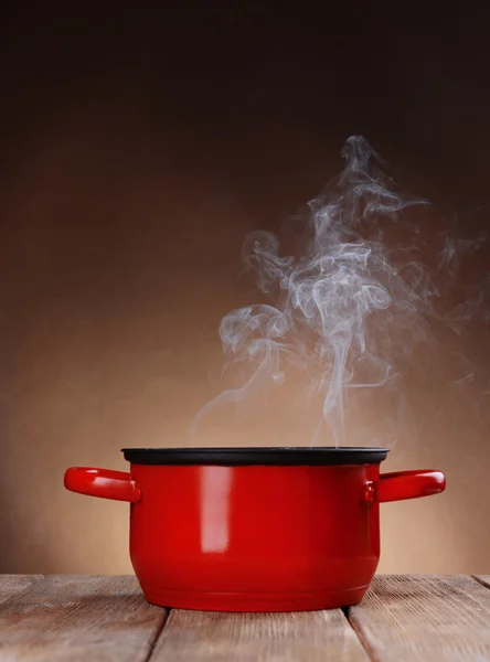 Panela de cozinha com vapor na mesa no fundo marrom — Fotografia de Stock