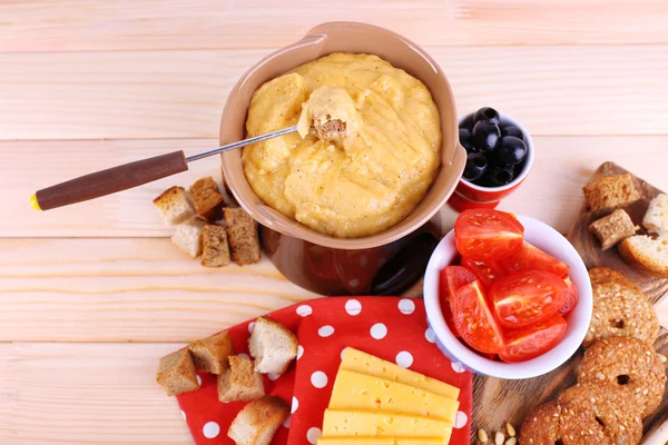 Fondue, tomaten, koekjes, plakjes kaas en beschuit op snijplank op polka dot servet op houten achtergrond — Stockfoto