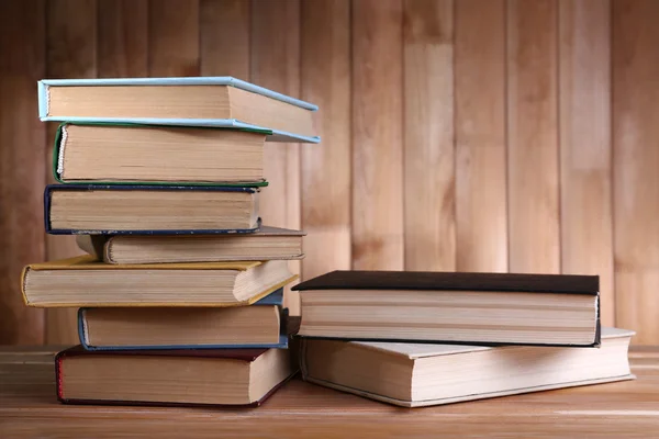Buku-buku di meja kayu dengan latar belakang dinding kayu — Stok Foto