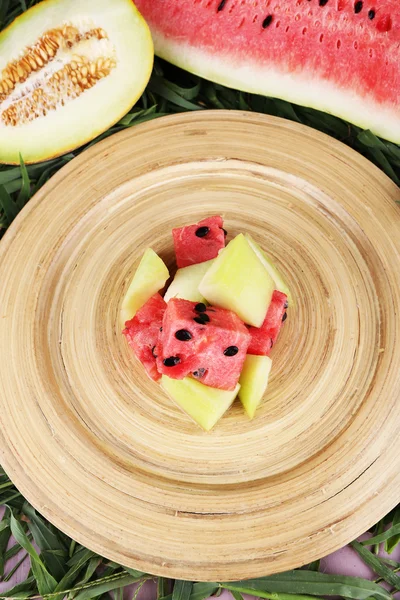 Melon and water melon on bamboo plate on grass background