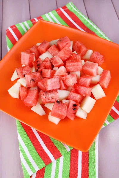 Wassermelonenscheiben in orangefarbenem Teller auf Serviette auf hölzernem Hintergrund — Stockfoto