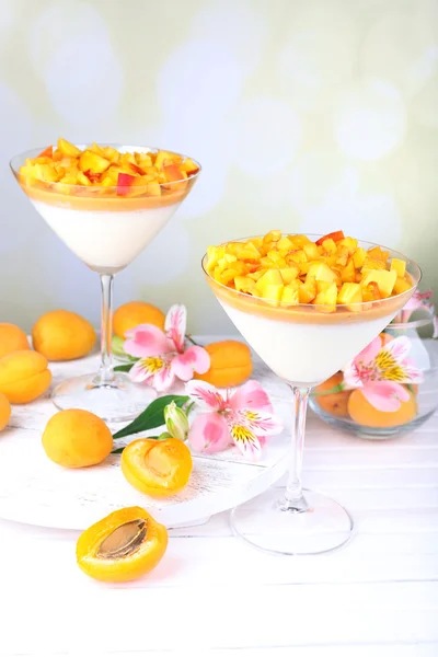 Apricot dessert in glasses on table on bright background — Stock Photo, Image