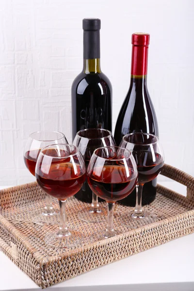 Glasses and wine bottle on tray in room — Stock Photo, Image