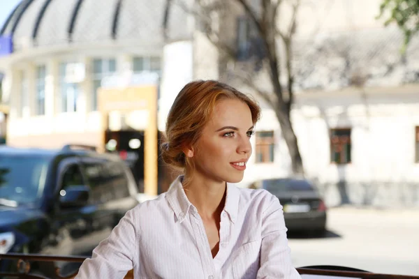 Beautiful young woman sitting in cafe — Stock Photo, Image