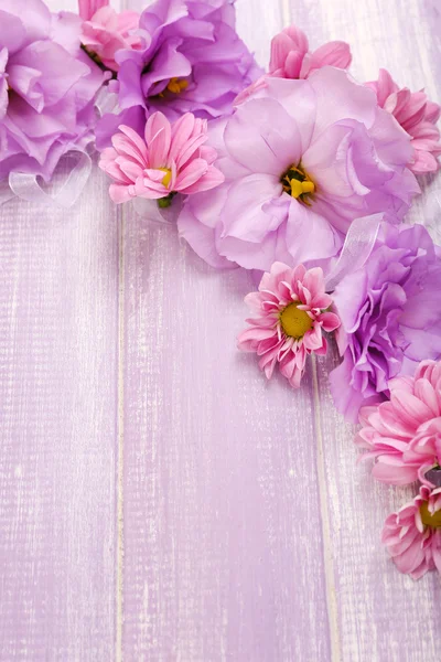 Beautiful chrysanthemum and artificial eustoma flowers on purple wooden background — Stock Photo, Image