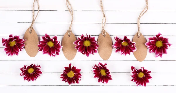 Hermosas flores de crisantemo y etiquetas vacías sobre fondo de madera blanca — Foto de Stock