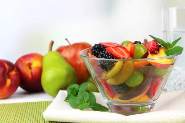 Frischer, schmackhafter Obstsalat auf Tisch, auf hellem Hintergrund — Stockfoto