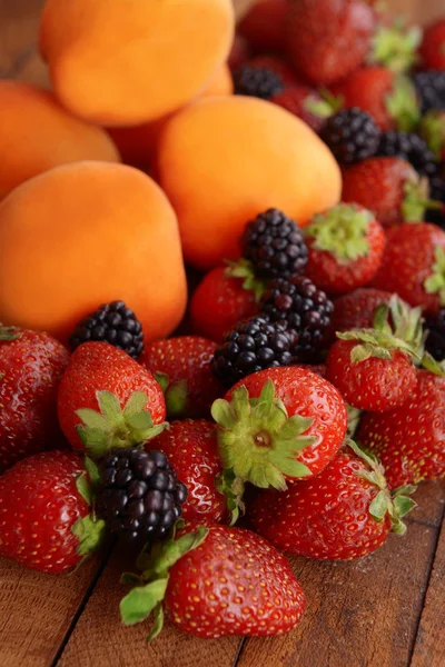 Ripe apricots and berries on wooden background — Stock Photo, Image