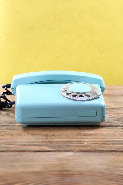 Retro turquoise telephone on wooden table, on color background — Stock Photo, Image