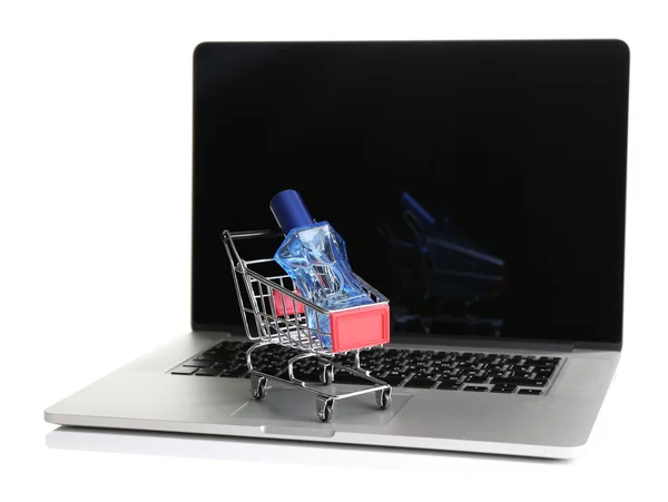 Botella de perfume en el carrito de la compra en el ordenador portátil aislado en blanco — Foto de Stock