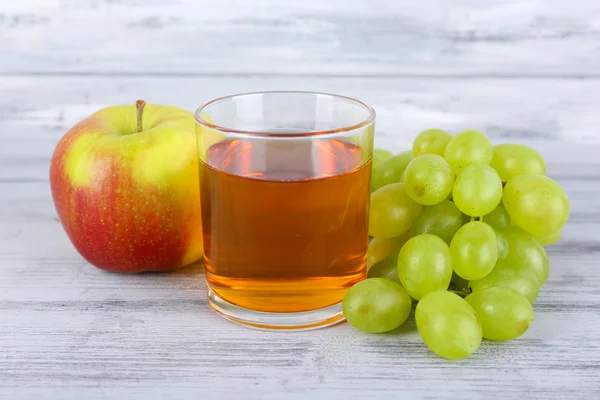 Glas Saft mit frischen Trauben und Apfel auf grauem Holztisch — Stockfoto