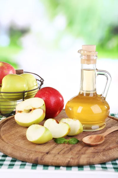 Äppelcidervinäger i glasflaska och mogna färska äpplen, på träbord, på natur bakgrund — Stockfoto