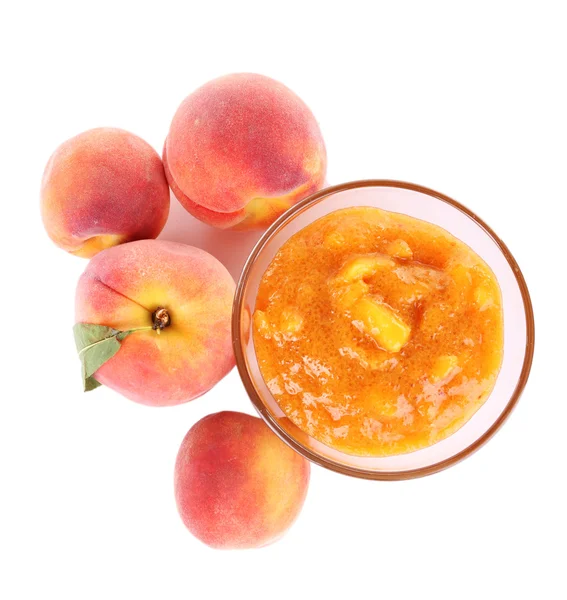 Вкусный персиковый джем со свежими персиками, изолированный на белом — стоковое фото