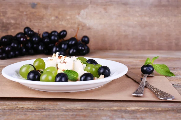 포도와 나무 테이블에 치즈 맛 있는 샐러드 — 스톡 사진