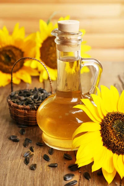 Sunflowers with seeds and oil on wooden background — Stock Photo, Image