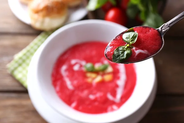 Gazpacho soep in de lepel en kom op houten achtergrond — Stockfoto