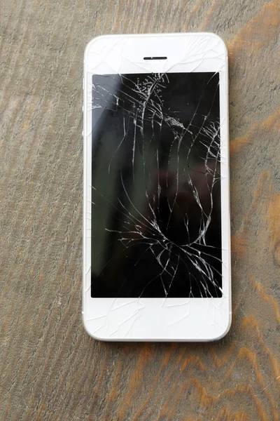 Modern mobile phone with broken screen on wooden background — Stock Photo, Image