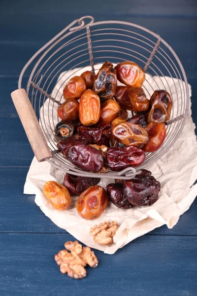 Tasty dates fruits in metal basket, on blue wooden table — Stock Photo, Image