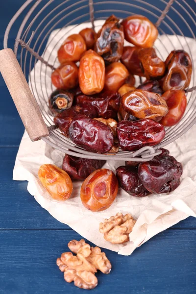 Tasty dates fruits in metal basket, on blue wooden table — Stock Photo, Image