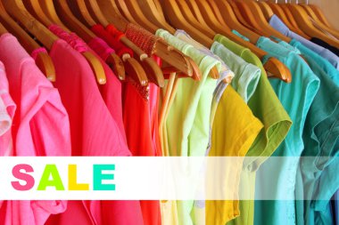 Concept of discount. Colorful clothes on hangers in wardrobe clipart