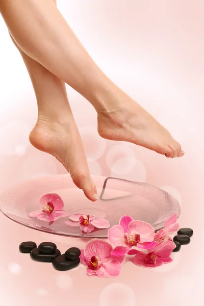 Vrouwelijke voeten in spa kom met water op lichte achtergrond — Stockfoto